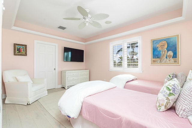 bedroom with a tray ceiling, light hardwood / wood-style flooring, and ceiling fan