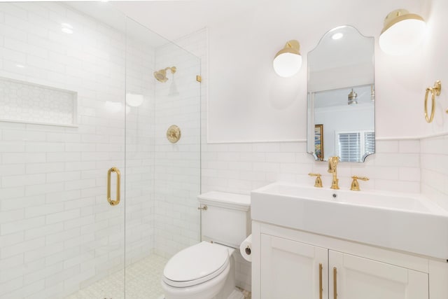 bathroom featuring vanity, toilet, tile walls, and a shower with shower door