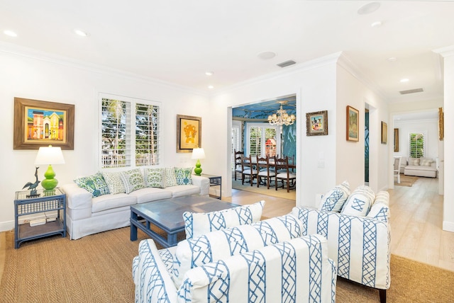 living room featuring light hardwood / wood-style floors, crown molding, and an inviting chandelier