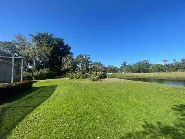 view of yard featuring a water view and glass enclosure