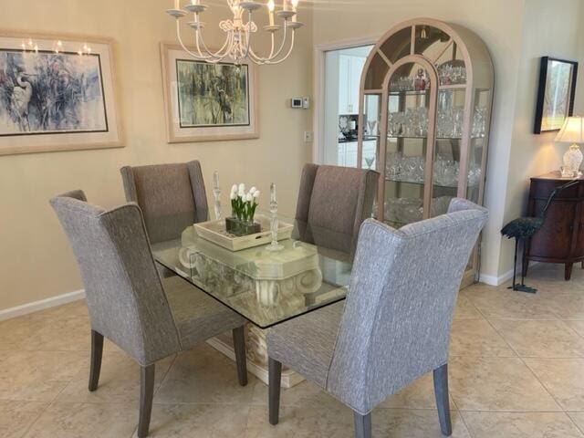 tiled dining space featuring an inviting chandelier and baseboards