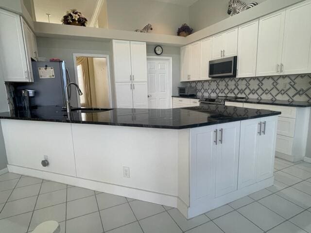 kitchen with a peninsula, backsplash, stainless steel appliances, and a sink