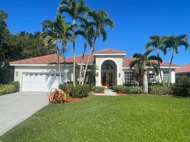 mediterranean / spanish-style house featuring an attached garage, french doors, decorative driveway, stucco siding, and a front yard