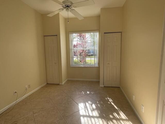 unfurnished room featuring a ceiling fan, baseboards, and tile patterned floors