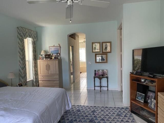 bedroom with arched walkways, tile patterned flooring, and a ceiling fan