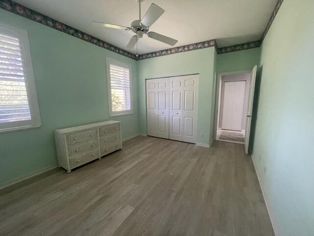 unfurnished bedroom with a ceiling fan, a closet, baseboards, and wood finished floors