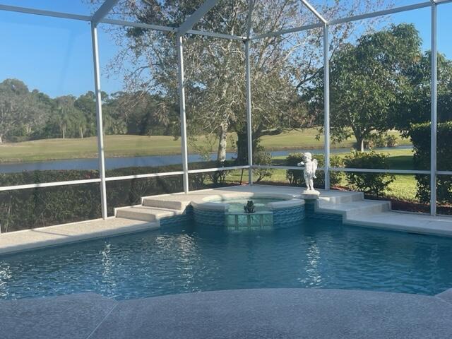 view of swimming pool featuring glass enclosure, a water view, and a pool with connected hot tub