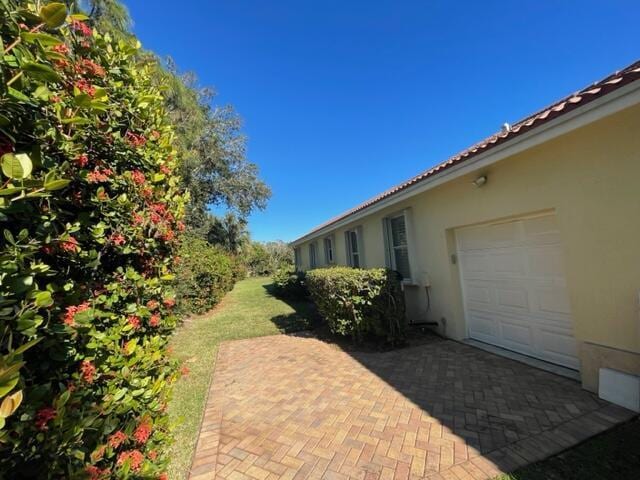 view of yard with a garage and decorative driveway