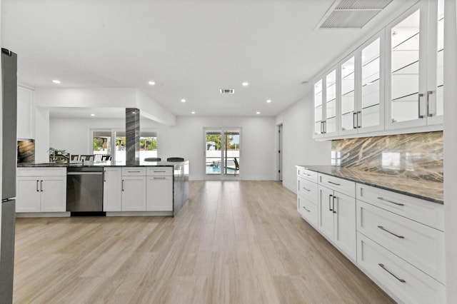 kitchen with white cabinets, stainless steel dishwasher, decorative backsplash, light hardwood / wood-style floors, and kitchen peninsula