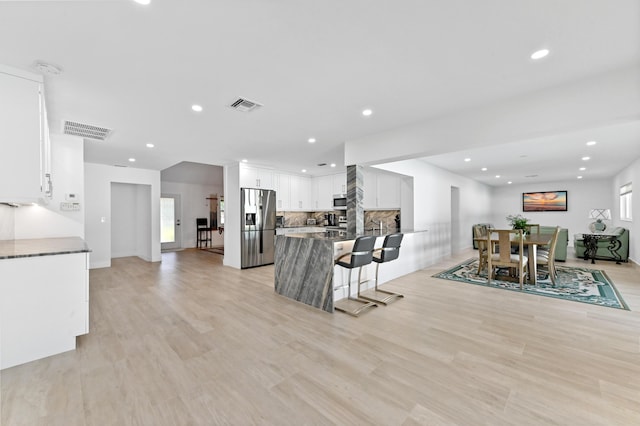 kitchen with a wealth of natural light, white cabinetry, light hardwood / wood-style flooring, and appliances with stainless steel finishes