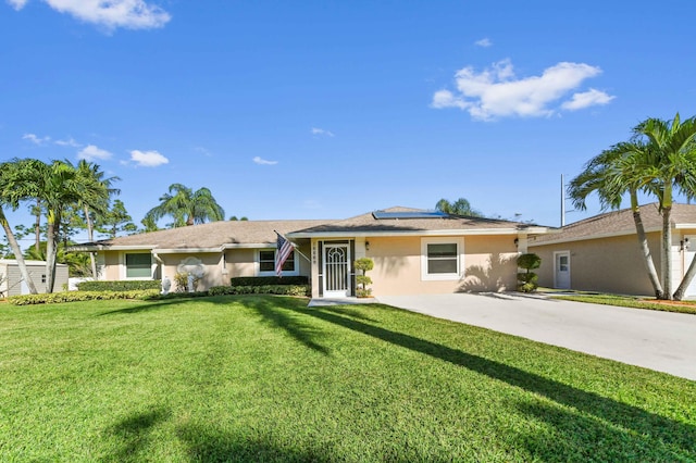 single story home with a front yard and solar panels