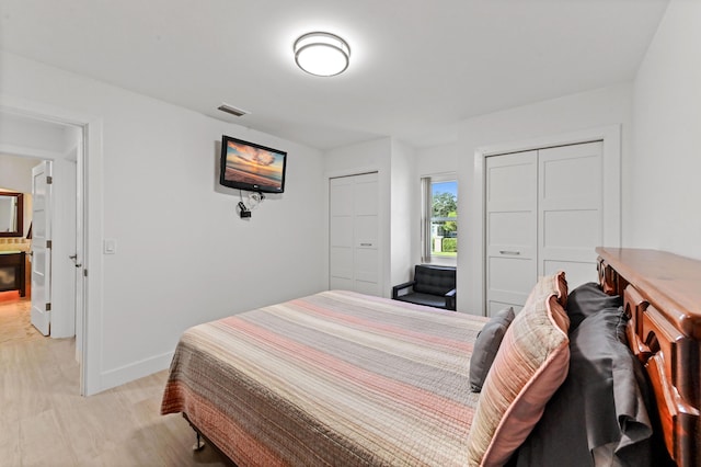 bedroom with multiple closets and light hardwood / wood-style flooring