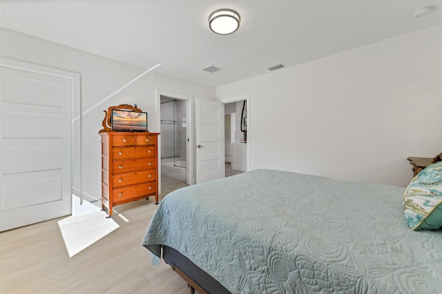 bedroom with connected bathroom and hardwood / wood-style floors