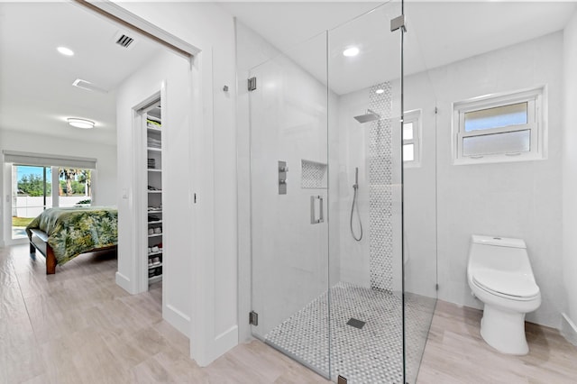 bathroom featuring toilet, wood-type flooring, and walk in shower