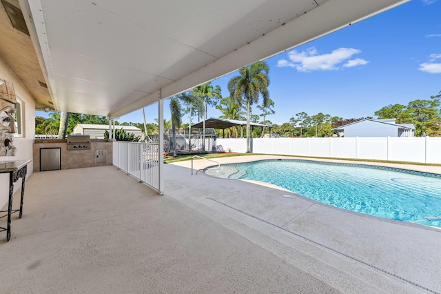 view of swimming pool featuring an outdoor kitchen, area for grilling, and a patio