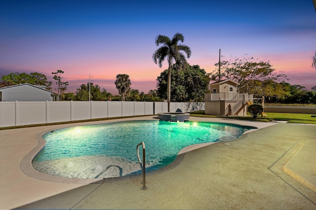 pool at dusk with a patio and an in ground hot tub