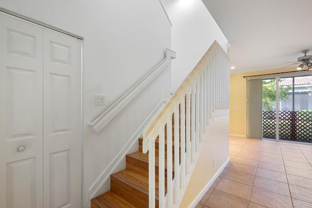 staircase with ceiling fan and tile patterned flooring