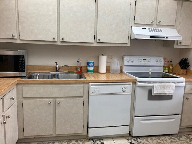 kitchen with sink, light tile patterned floors, and white appliances