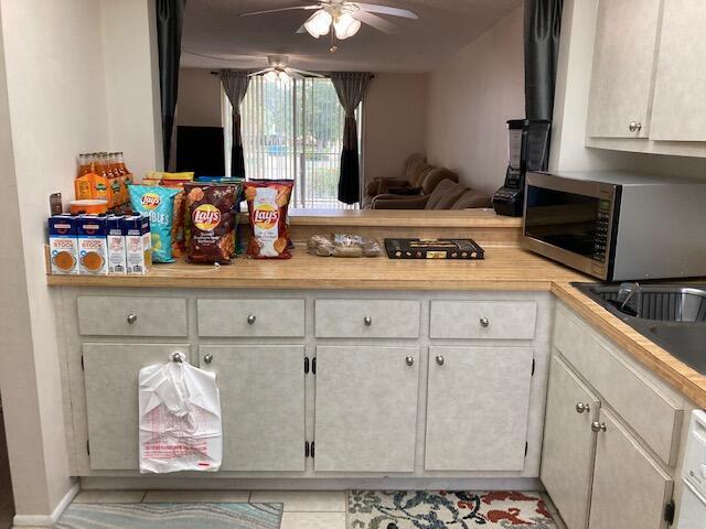 kitchen with white cabinets, sink, ceiling fan, and light tile patterned flooring