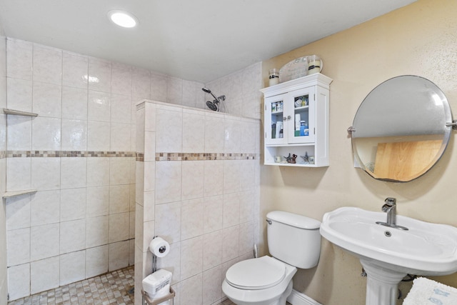 bathroom featuring toilet, a tile shower, and sink