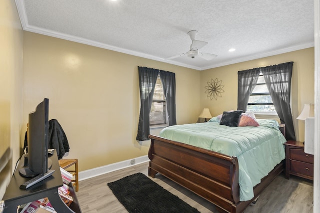 bedroom featuring a textured ceiling, ceiling fan, light wood-type flooring, and ornamental molding