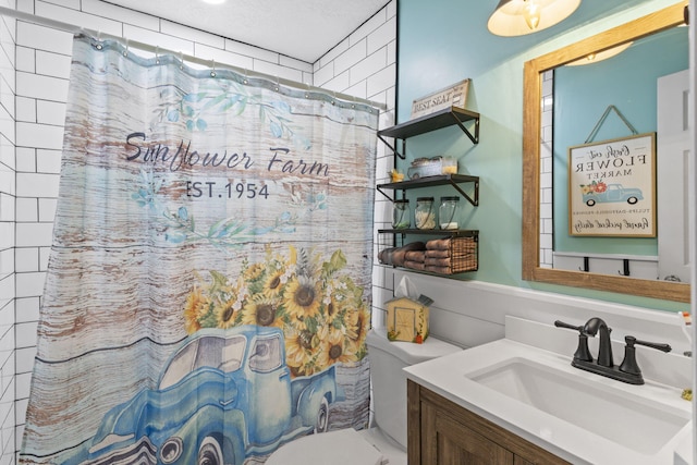 bathroom featuring walk in shower, vanity, a textured ceiling, and toilet