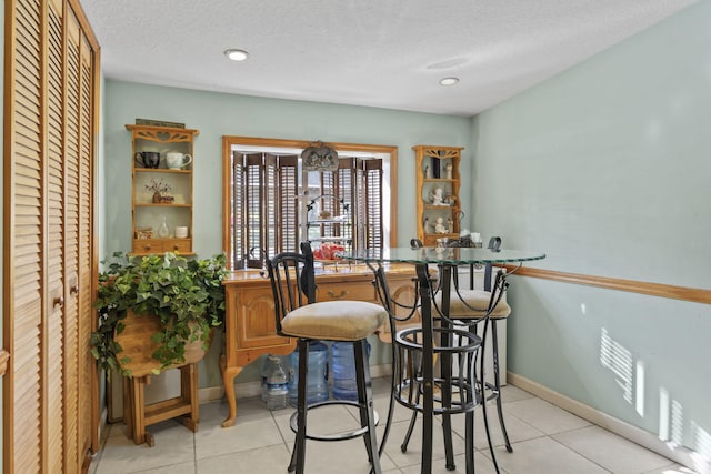 dining space with light tile patterned floors and a textured ceiling