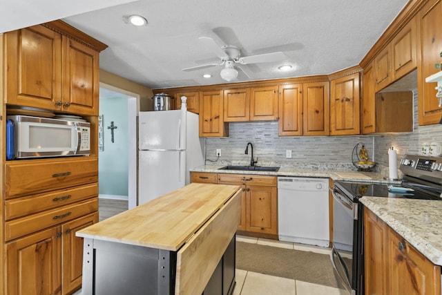 kitchen with a center island, wooden counters, sink, light tile patterned floors, and stainless steel appliances