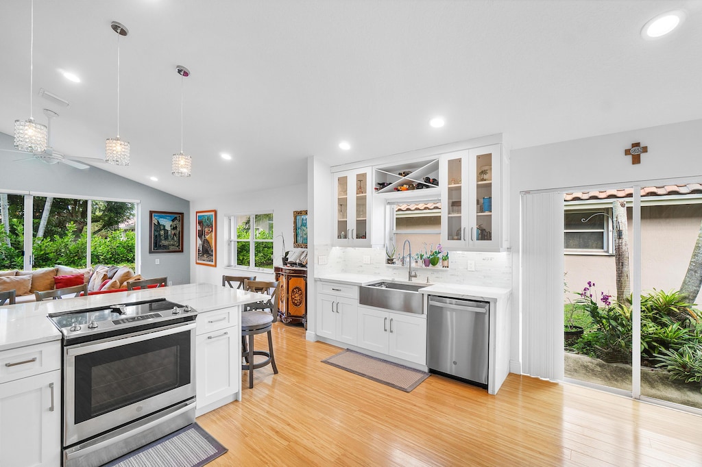 kitchen with pendant lighting, sink, white cabinetry, stainless steel appliances, and decorative backsplash