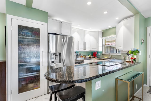 kitchen featuring stainless steel fridge, a breakfast bar, white cabinets, and light tile patterned flooring