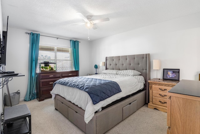 bedroom with ceiling fan, light colored carpet, and a textured ceiling