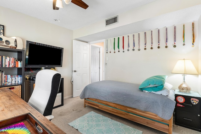 bedroom featuring ceiling fan, light carpet, and a textured ceiling