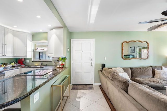 kitchen featuring white cabinetry, sink, ceiling fan, dark stone counters, and light tile patterned floors