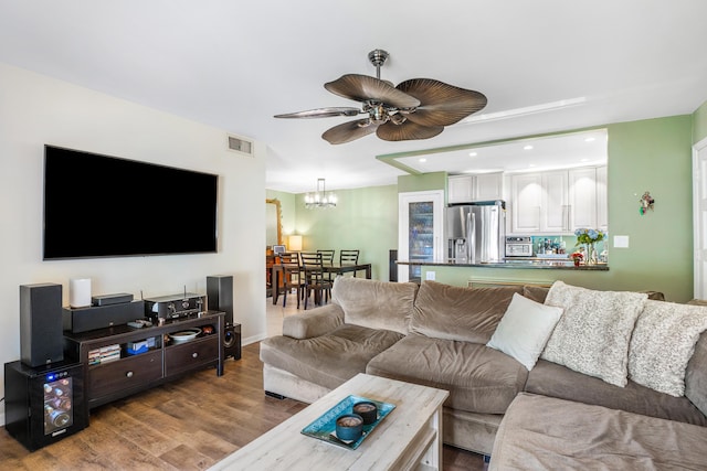 living room with hardwood / wood-style flooring and ceiling fan with notable chandelier