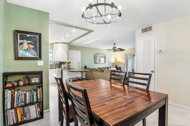 tiled dining space with ceiling fan with notable chandelier