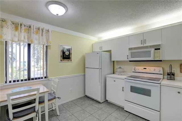 kitchen featuring white cabinets, light tile patterned flooring, white appliances, and a textured ceiling