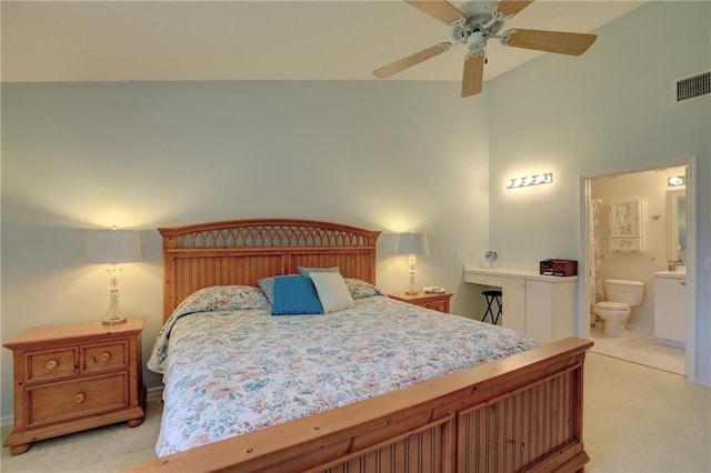 carpeted bedroom with ensuite bathroom, high vaulted ceiling, and ceiling fan