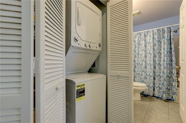 laundry area featuring light tile patterned floors and stacked washer / dryer