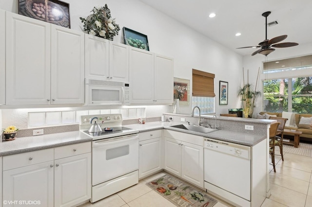 kitchen with kitchen peninsula, white appliances, sink, light tile patterned floors, and white cabinetry