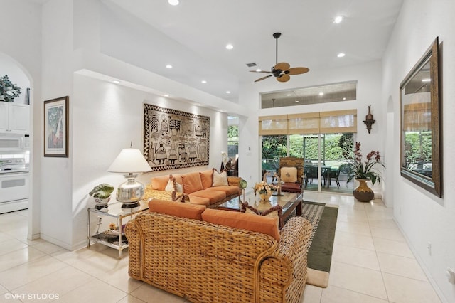 living room featuring light tile patterned floors, ceiling fan, and a high ceiling