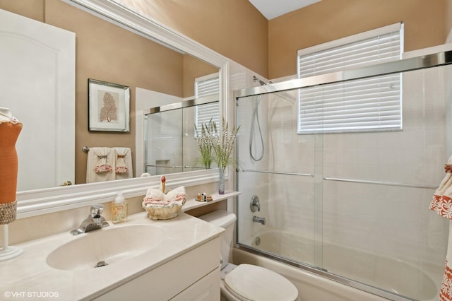 full bathroom featuring shower / bath combination with glass door, plenty of natural light, vanity, and toilet