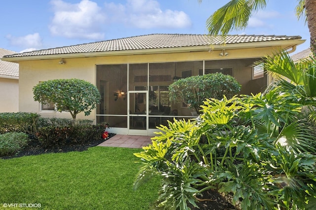 rear view of property with a sunroom and a lawn