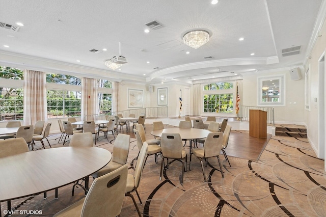 dining area featuring a notable chandelier, plenty of natural light, ornamental molding, and a textured ceiling