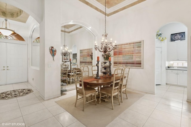 dining room featuring a towering ceiling, a tray ceiling, a notable chandelier, and light tile patterned flooring