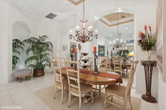 dining space featuring a raised ceiling, light tile patterned floors, and a notable chandelier