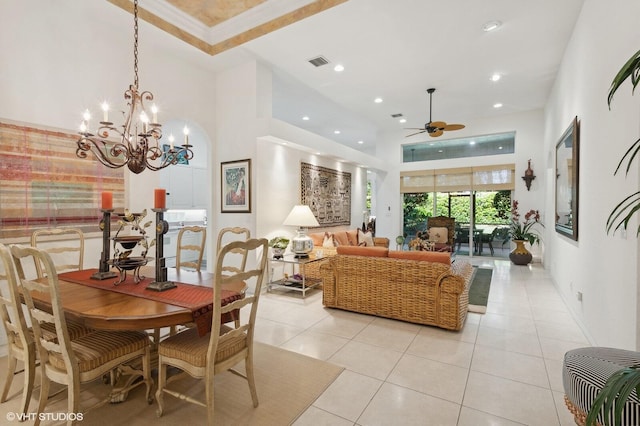 tiled dining room with ceiling fan with notable chandelier, ornamental molding, and a high ceiling