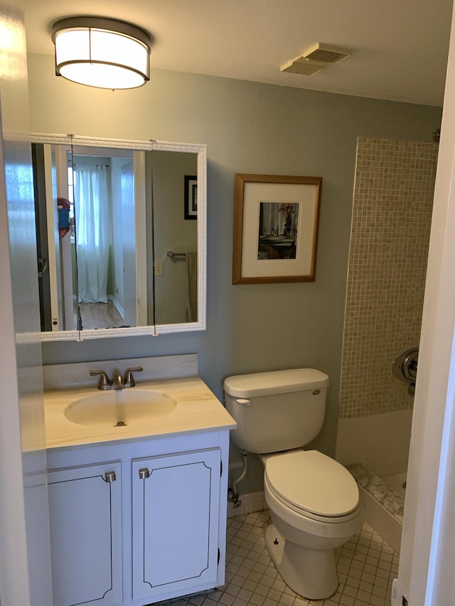 bathroom featuring tile patterned floors, vanity, tiled shower, and toilet