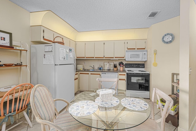 kitchen with white appliances, cream cabinets, sink, tasteful backsplash, and light tile patterned flooring