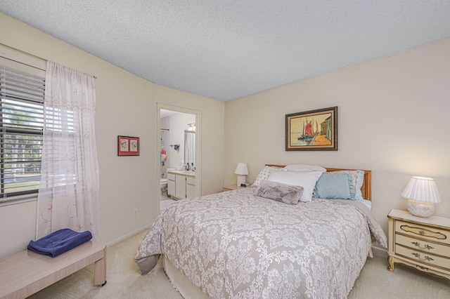 carpeted bedroom with connected bathroom and a textured ceiling