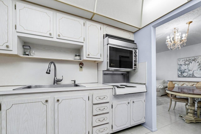 kitchen with white stovetop, sink, a notable chandelier, white cabinets, and light tile patterned flooring